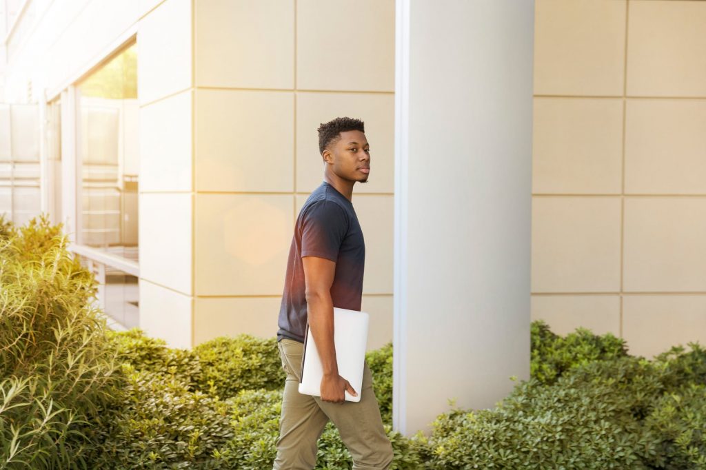 student walks to campus with laptop